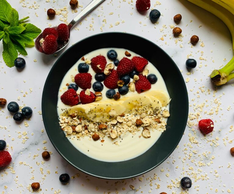Delicious fruit and yogurt bowl with berries, banana, and nuts for a nutritious breakfast.