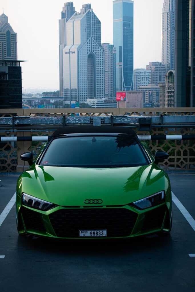 A stylish green Audi car parked with the iconic Dubai skyline as the backdrop, showcasing urban luxury and architecture.